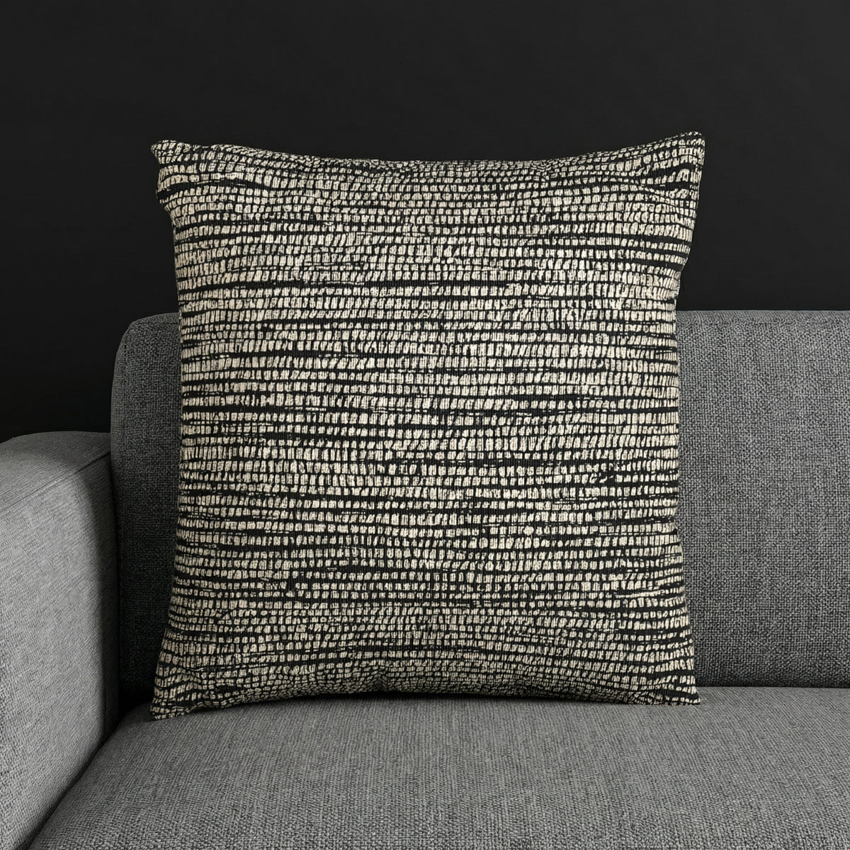 Woven textured cushion with black and cream pattern on a gray sofa, Edward Gorey shop decor