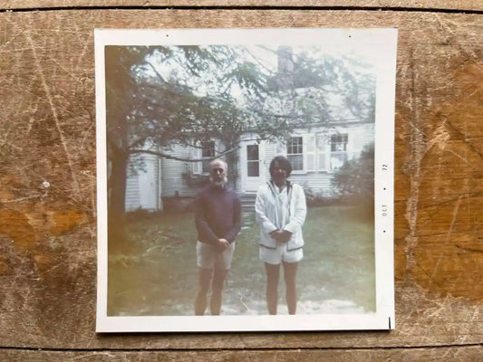 Vintage photo of two people standing in front of a white house, outdoor setting, Edward Gorey
