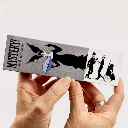 Edward Gorey Mystery flipbook held in hands with gothic illustration and Victorian characters