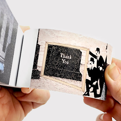 Hands flipping Edward Gorey flipbook page showing illustration with 'Thank You' sign