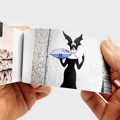 Hands flipping through Edward Gorey flipbook with gothic character illustration