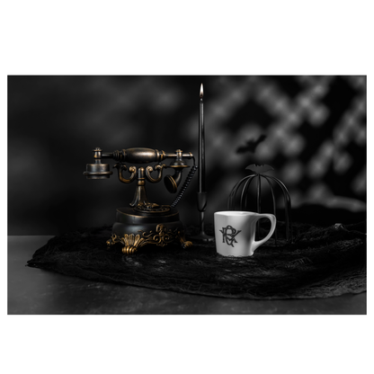 Edward Gorey mug on black lace next to vintage telephone, candle, and bat cage display